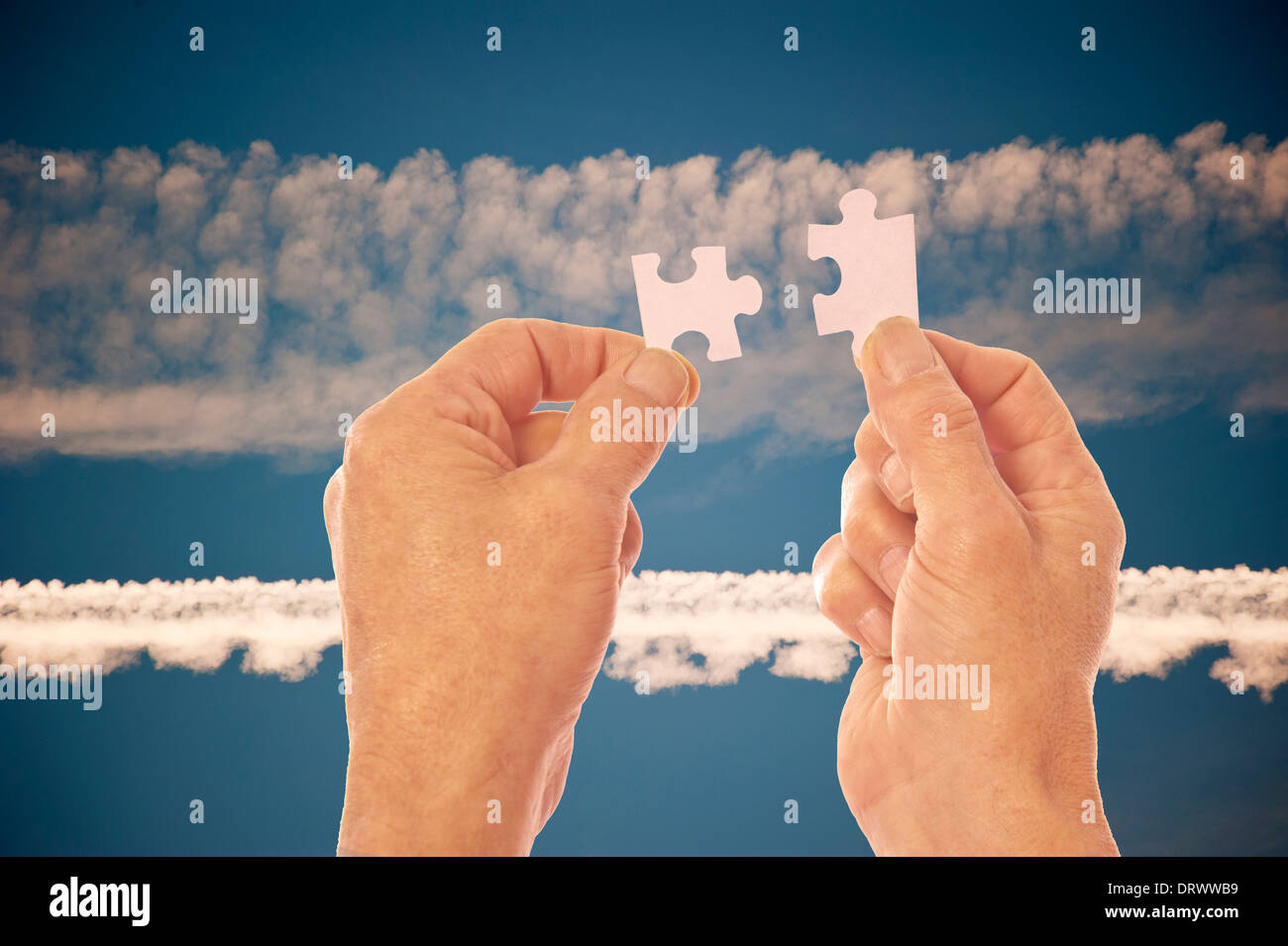 Zwei Hände in der Silhouette vor einem blauen Himmel mit Vapor Trails verbinden Jigsaw Puzzle-Teile Stockfoto