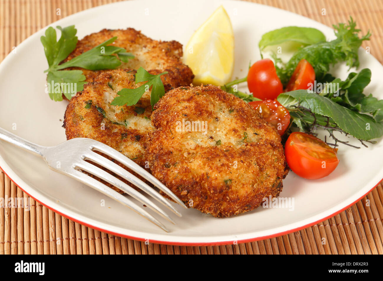 Hausgemachte Fischfrikadellen mit Salat und Zitrone Stockfoto