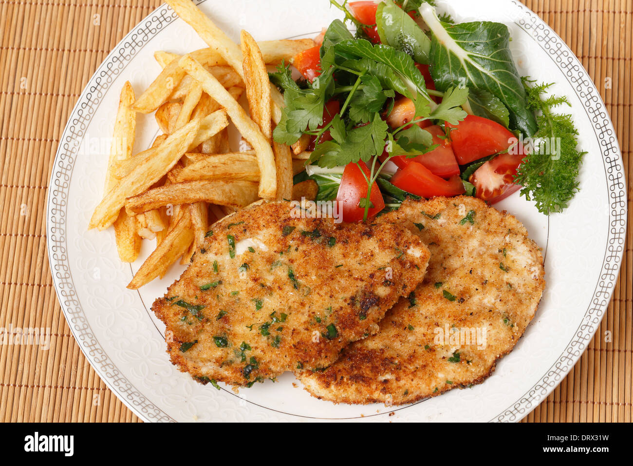 Panierte Chicken Schnitzel oder Schnitzel mit Pommes frites, Tomaten und grüner Salat Stockfoto