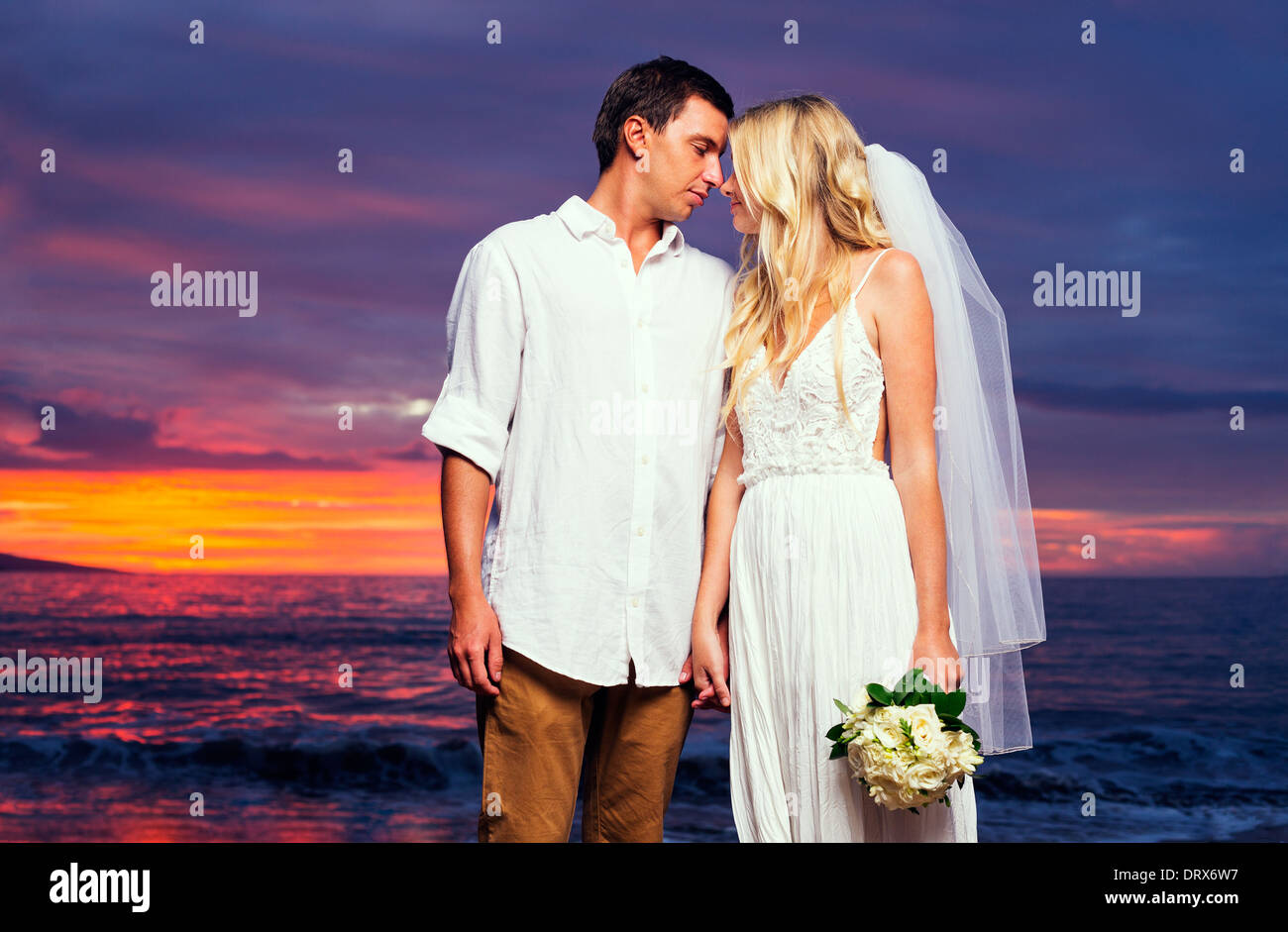 Ein verheiratetes Paar, Braut und Bräutigam, bei Sonnenuntergang an einem wunderschönen tropischen Strand Stockfoto