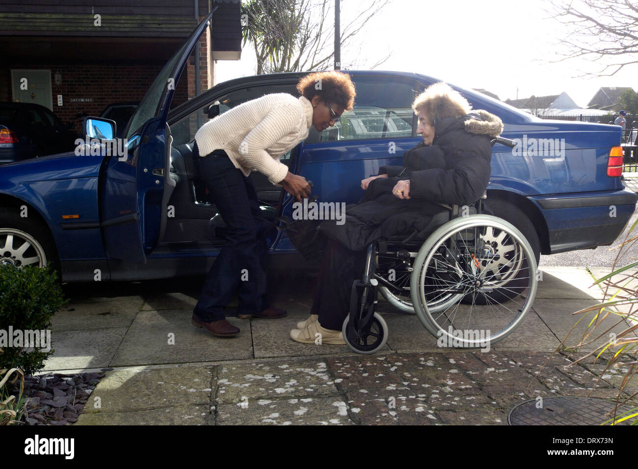 Vereinigtes Königreich West Sussex eine ältere Frau in ein Auto steigen von Betreuer geholfen Stockfoto