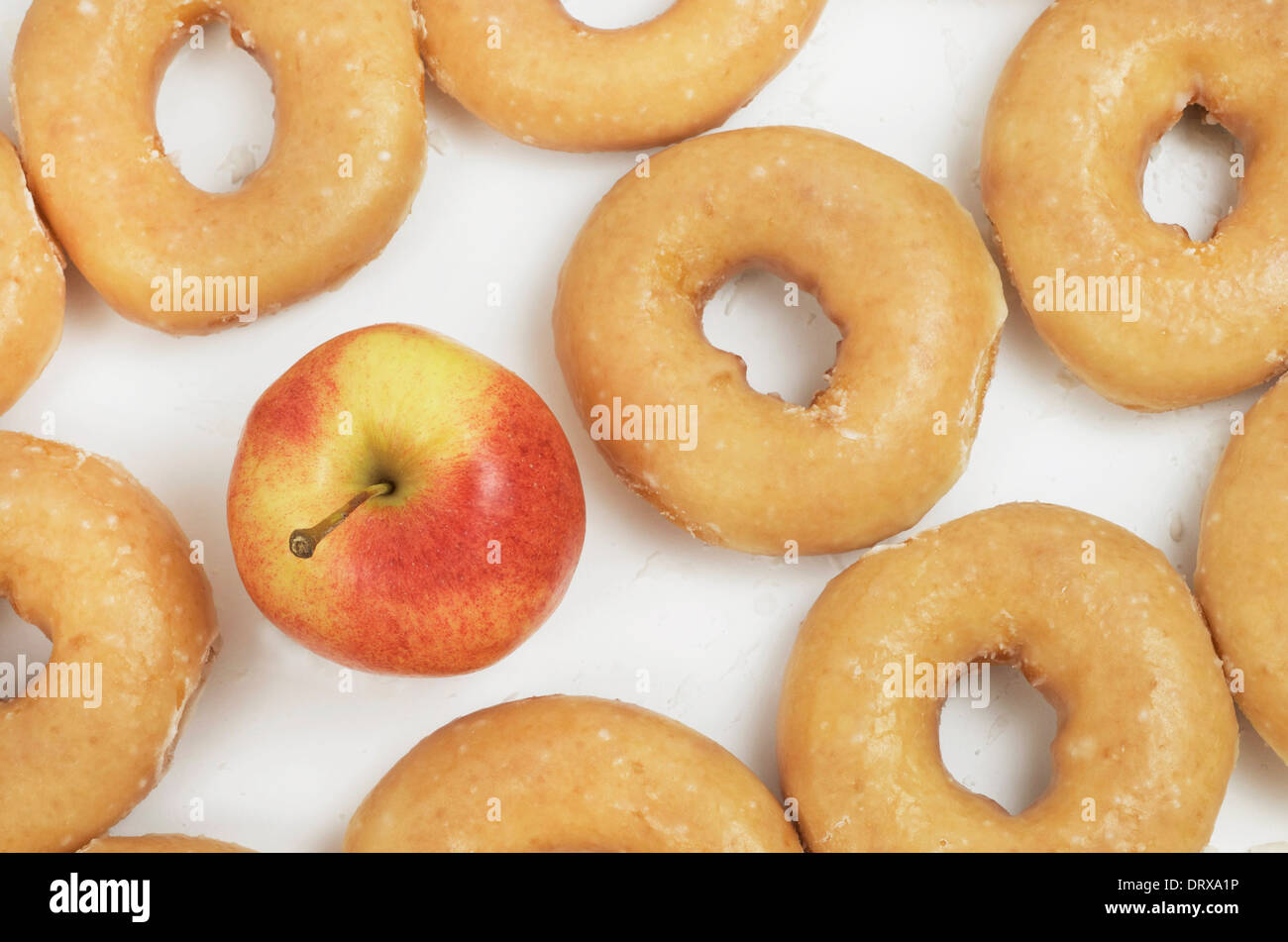 Roter Apfel ersetzt einen Donut in ein paar Zeilen von Donuts diagonal abgebildet. Stockfoto