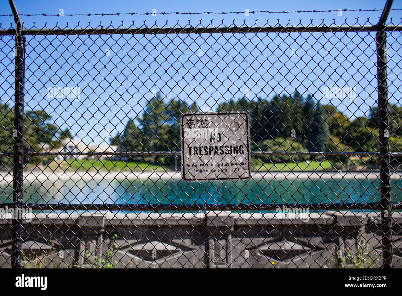 Aufnahme eines No Trespassing Zeichens ein Maschendrahtzaun umgeben ein Reservoir, Seattle, Washington. Stockfoto