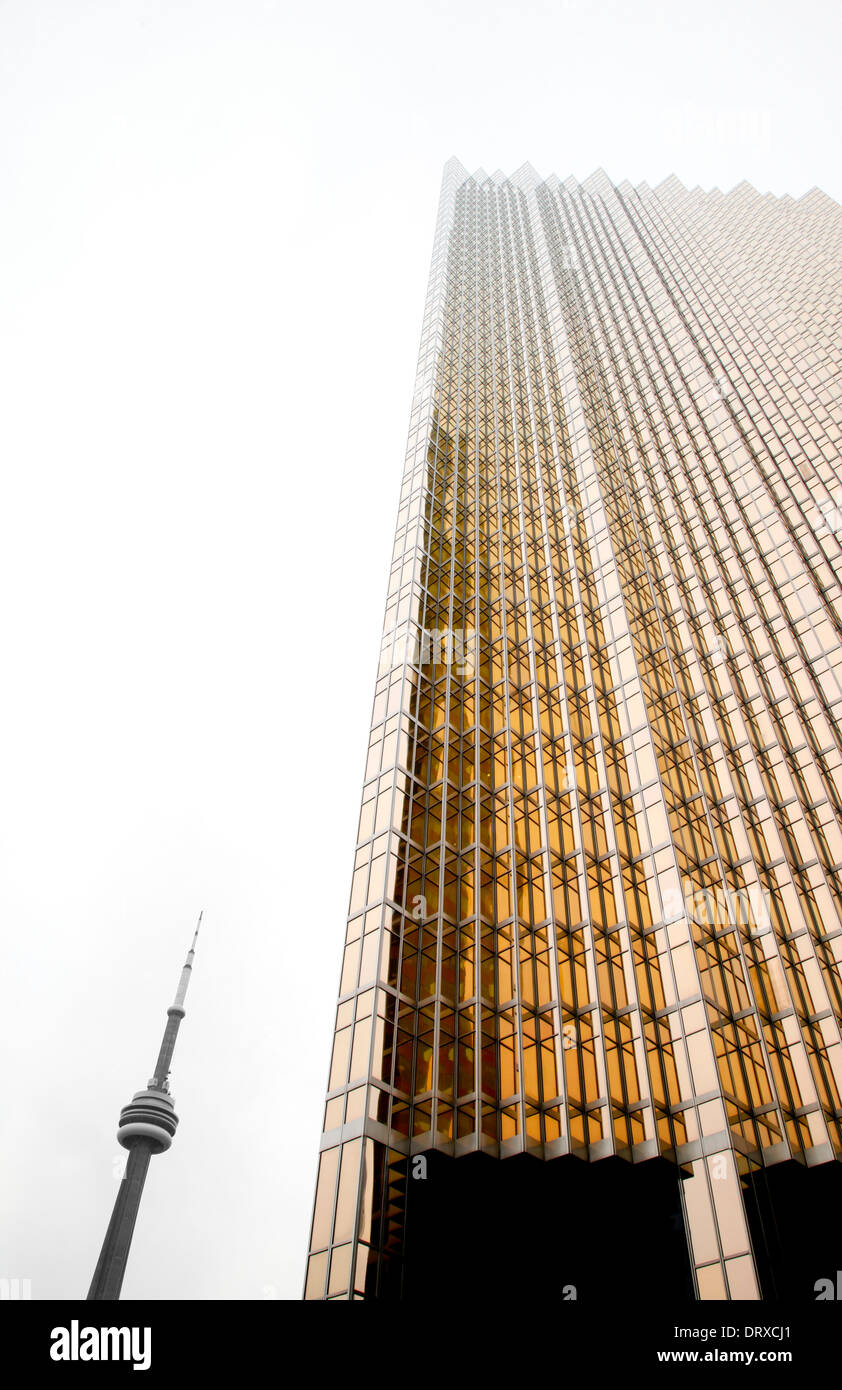 Der CN Tower in Toronto, Ontario Kanada zeigt sich an einem nebeligen Tag neben einer goldenen Skyscapper, Stockfoto