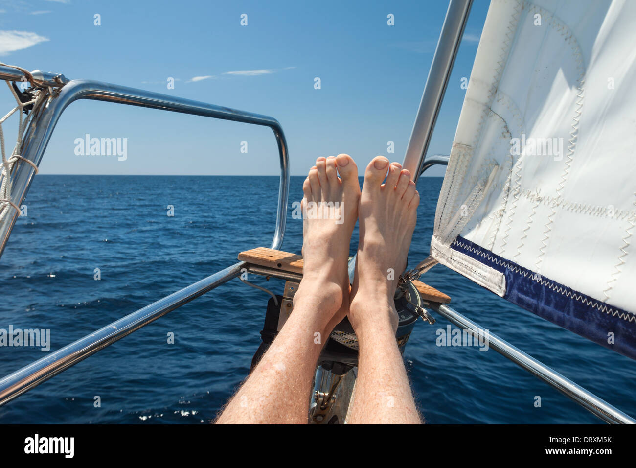 Man entspannt seine Füße auf einem Segelboot. Stockfoto