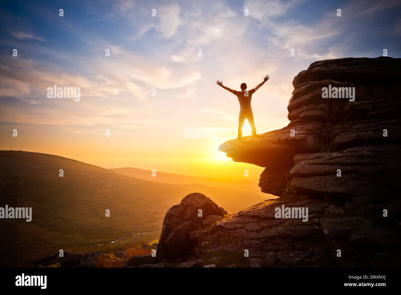 Eine Person mit dem Ausdruck ihrer Freiheit - bis in den Himmel gegen einen Sonnenuntergang zu erreichen. Stockfoto