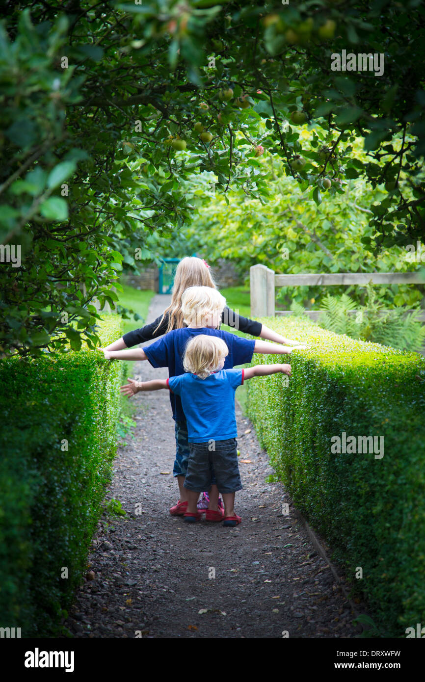 Drei Geschwister, die zu Fuß in einem Garten Stockfoto
