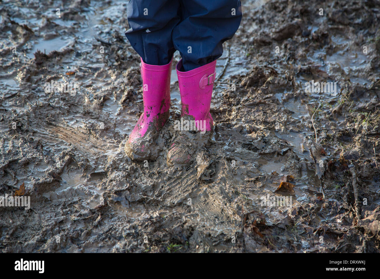 Junges Mädchen in Gummistiefeln im Schlamm Stockfoto