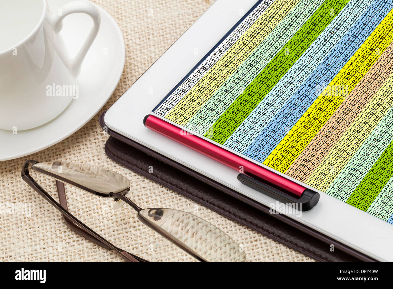 Daten-Tabelle auf einem digitalen Tablet mit einer Tasse Kaffee und Lesebrille Stockfoto