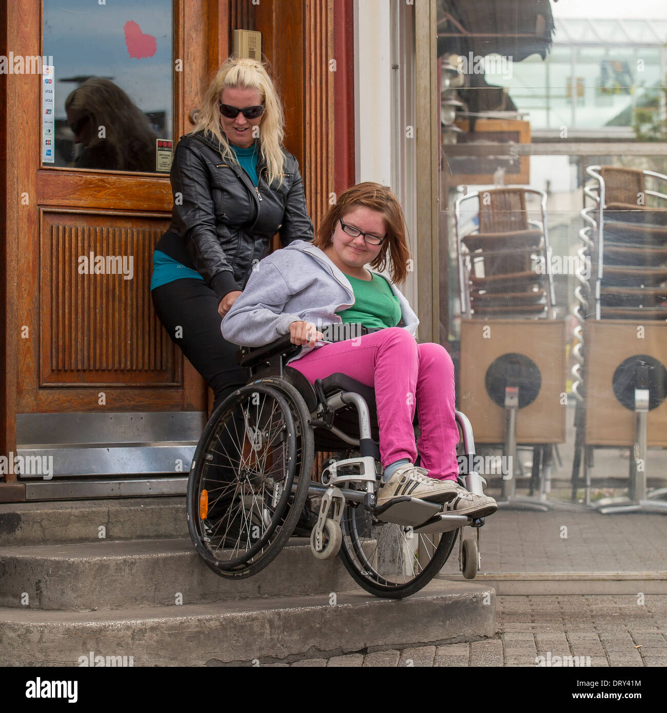 Betreuer helfen behinderten Mädchen im Rollstuhl die Treppe hinauf, Reykjavik, Island Stockfoto
