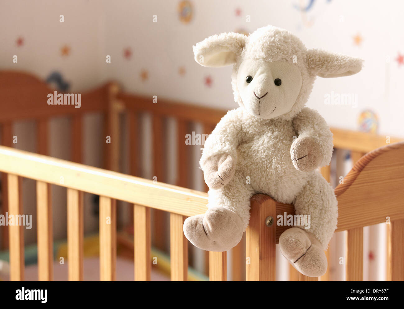 Kuschelige Schafe sitzt auf einem Kinderbett. Stockfoto