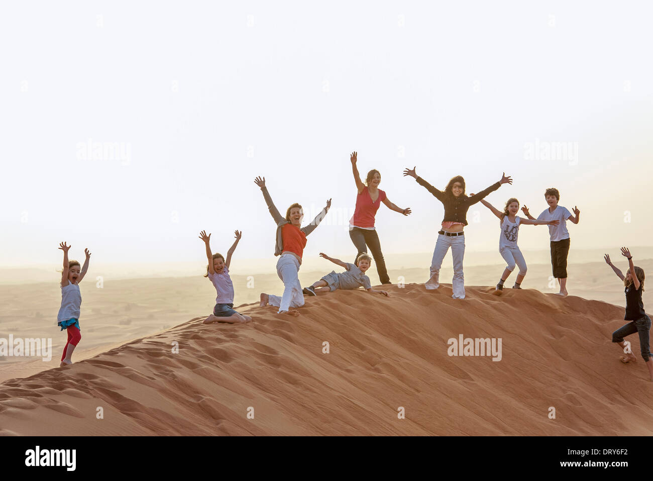 Gruppe von Menschen, die stehen auf einsamen Düne mit Luft erhobenen Armen Stockfoto