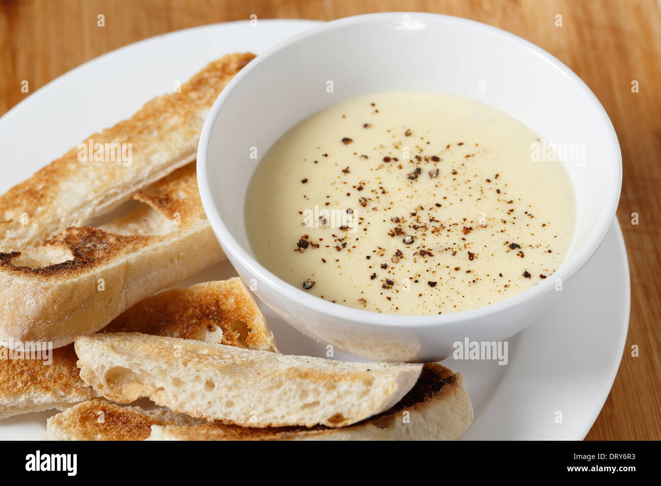 Käse-Dip mit Frischkäse, Milch, Ei und Butter in einer Bain Marie, mit Pfeffer bestreut mit Ciabata Crostini serviert gemacht. Stockfoto