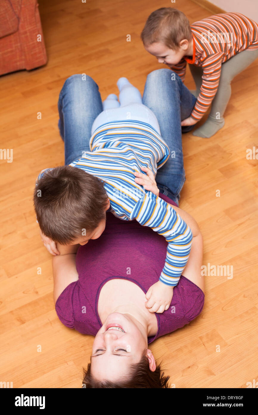 Glückliche Mutter mit Kindern auf dem Boden zu Hause spielen Stockfoto