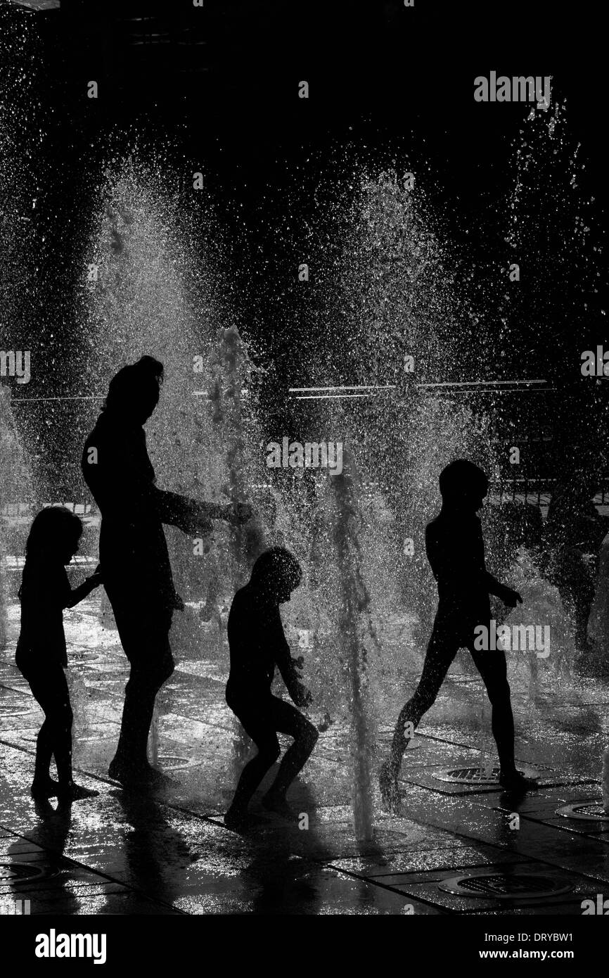 Silhouetten von Menschen spielen im Wasser-Brunnen. Stockfoto