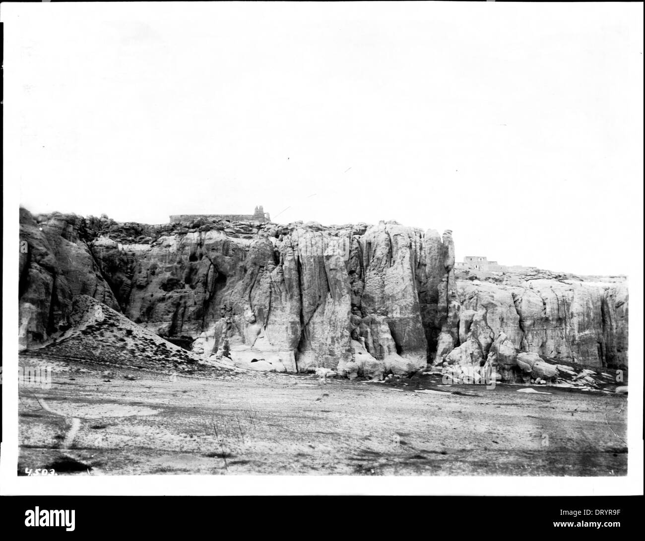 Ein Foto, das um 1900 die alte Kirche von Acoma Pueblo zeigt, vom Fuße der Mesa Encantada aus gesehen, was die architektonische und kulturelle Bedeutung der Stätte veranschaulicht. Stockfoto