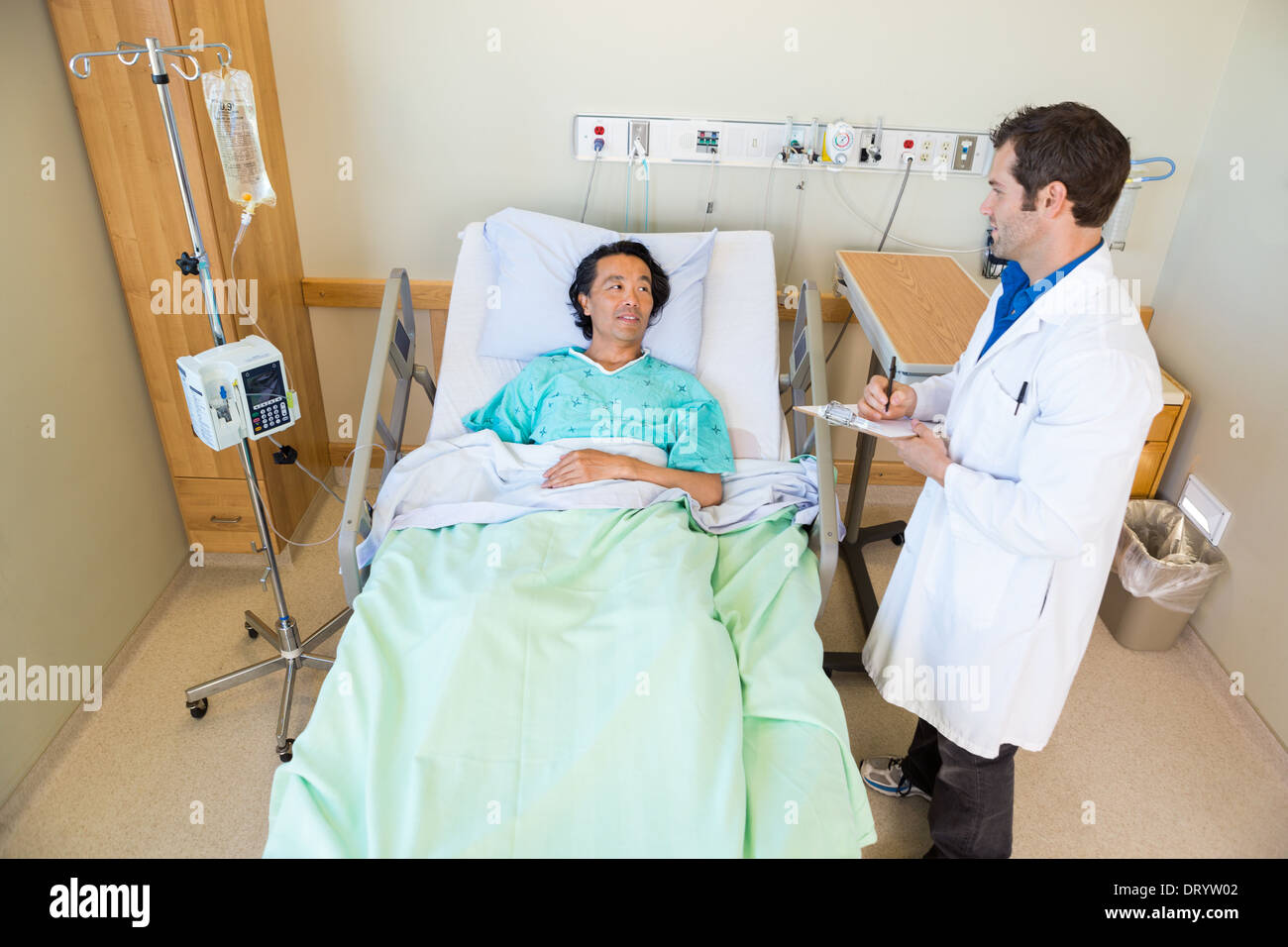 Männlichen Arzt Blick auf Patienten beim Schreiben von Notizen in Zwischenablage Stockfoto