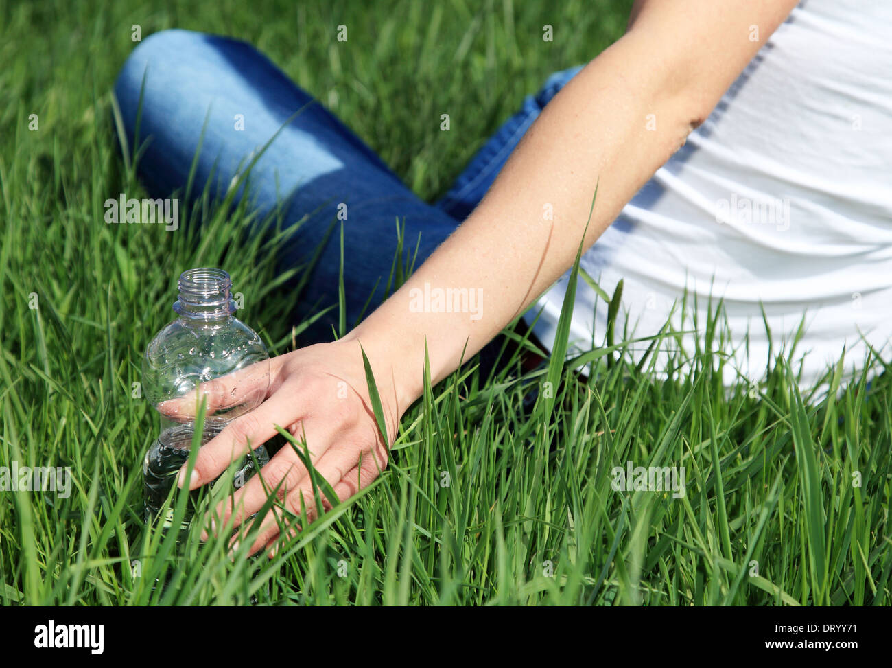 Person Trinkwasser draußen auf der grünen Wiese Stockfoto