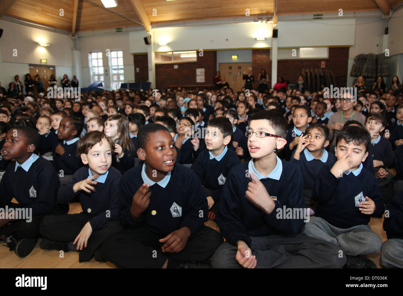 Kinder singen und Gebärdensprache auf einer Schulversammlung durchführen. Einige sind taub oder schwerhörig. Stockfoto