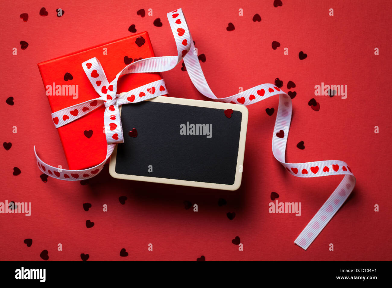 Geschenkbox mit gerahmten Tafel auf rotem Papierhintergrund. Valentines Day. Ansicht von oben Stockfoto