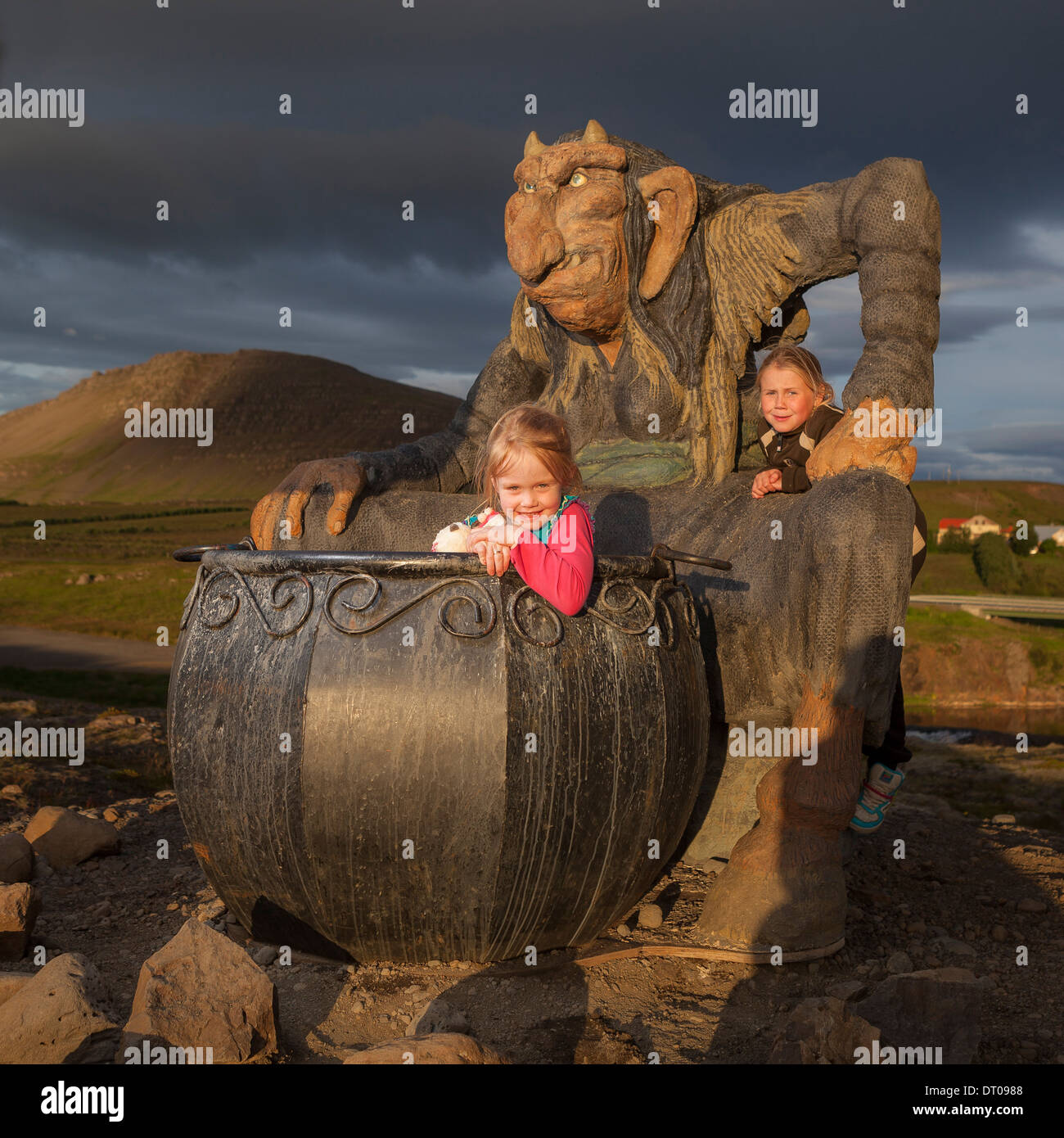 Mädchen spielen in einem großen Kessel mit Statue von Gryla, Island Stockfoto