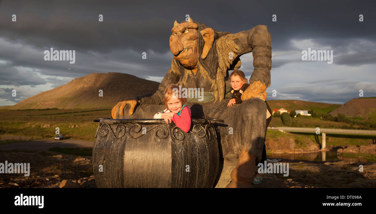 Mädchen spielen in einem großen Kessel mit Statue von Gryla, Island Stockfoto