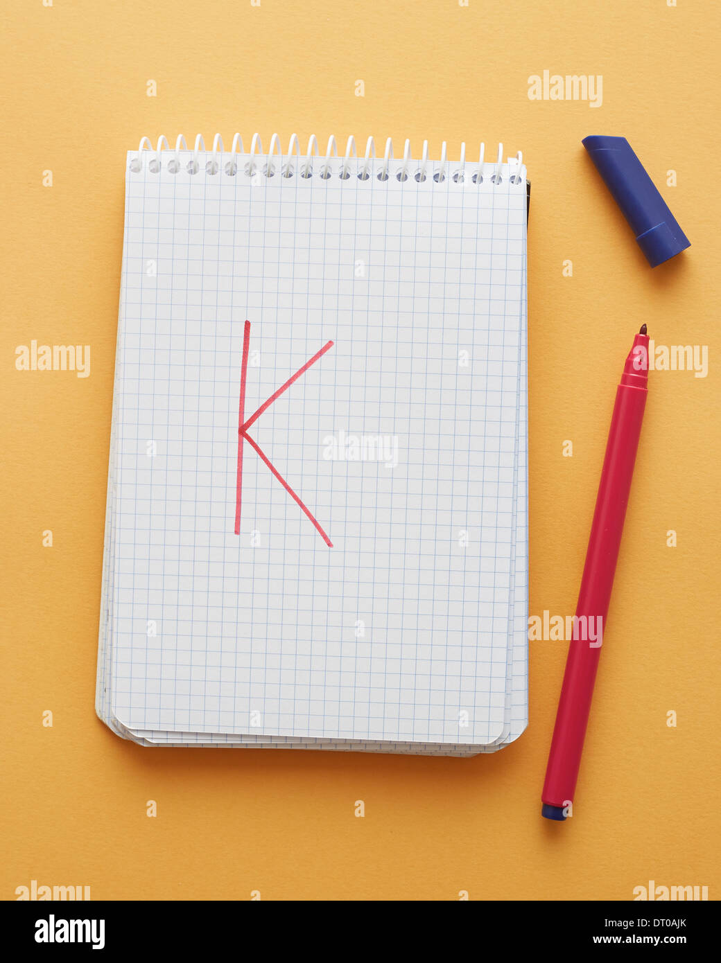 K-Brief handschriftlich in Notizblockseite auf gelbem Hintergrund alphabet Stockfoto