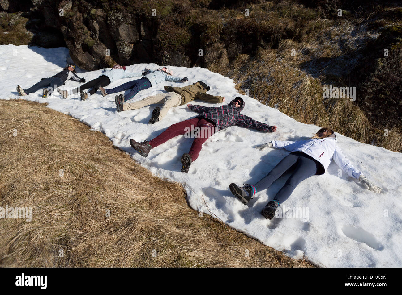 Jugendliche auf ein Patch von Schnee von Oxarafoss Wasserfällen, Thingvellir National Park liegen. Stockfoto