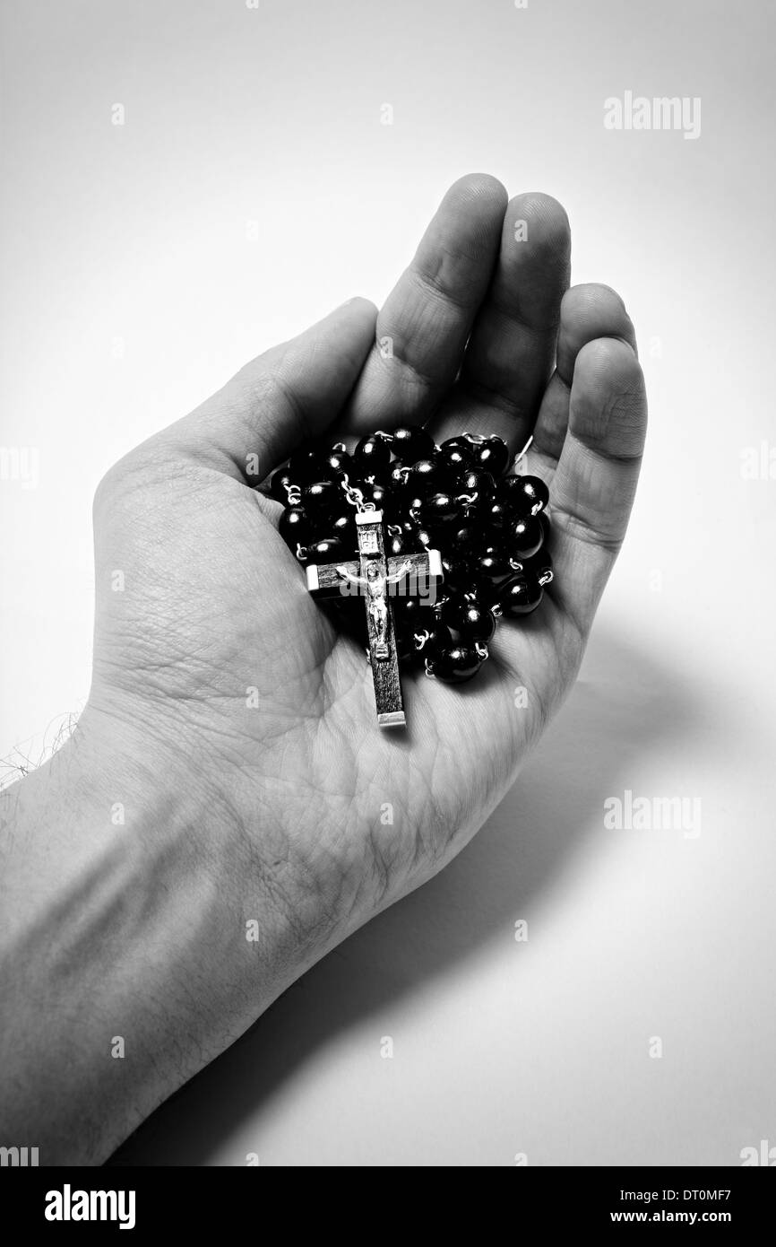 Mannes Hand mit hölzernen Rosenkranz mit katholischen Kreuz auf weißem Hintergrund Stockfoto