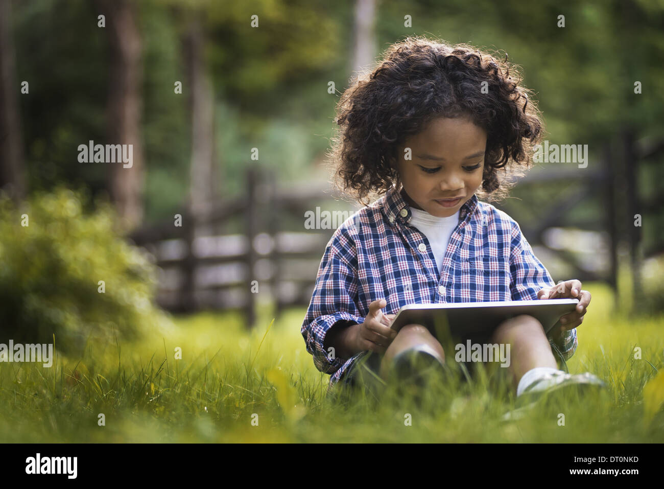 Woodstock, New York USA kleiner Junge sitzt auf dem Rasen mit Tablet-PC Stockfoto