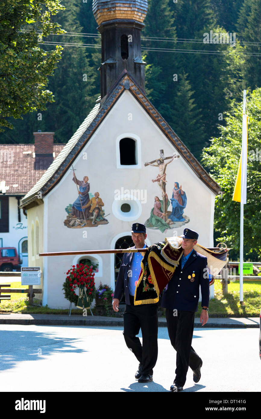 Soldaten tragen zeremonielle Flagge vorbei an St. Peter und Paul in das Dorf von Klais in Bayern, Deutschland Stockfoto