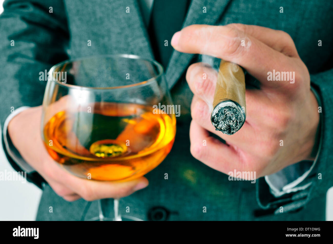 ein Mann trägt einen Anzug mit einer Zigarre und einem Glas Brandy Stockfoto