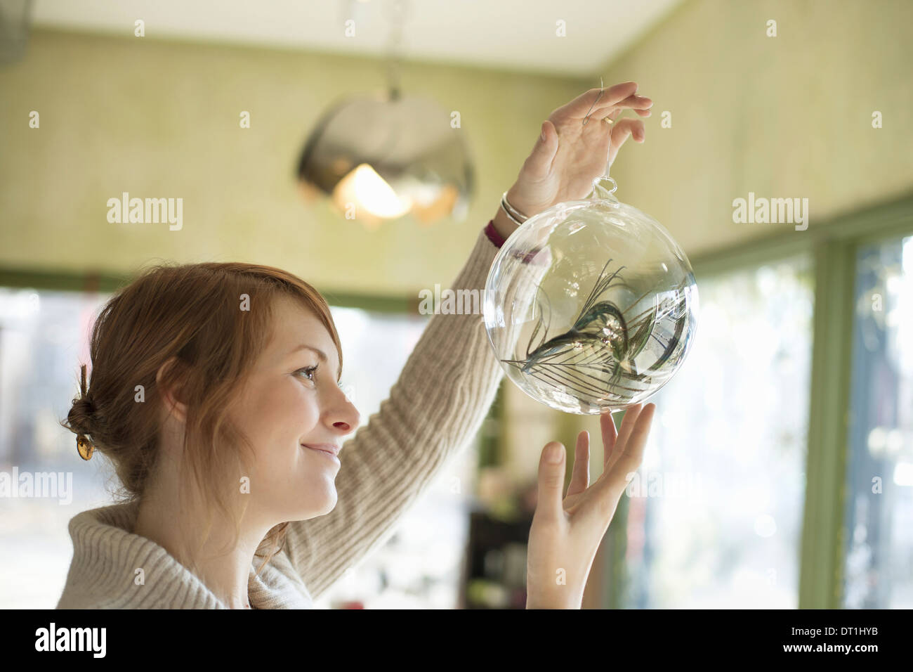 Eine Frau hält eine große Glaskugel mit einem dekorativen Gegenständen in Klarglas Stockfoto