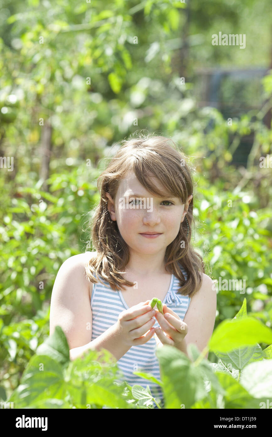Ein junges Mädchen unter den frischen grünen Laub Garten Gemüse und Blumen pflücken frisches Gemüse im sitzen Stockfoto