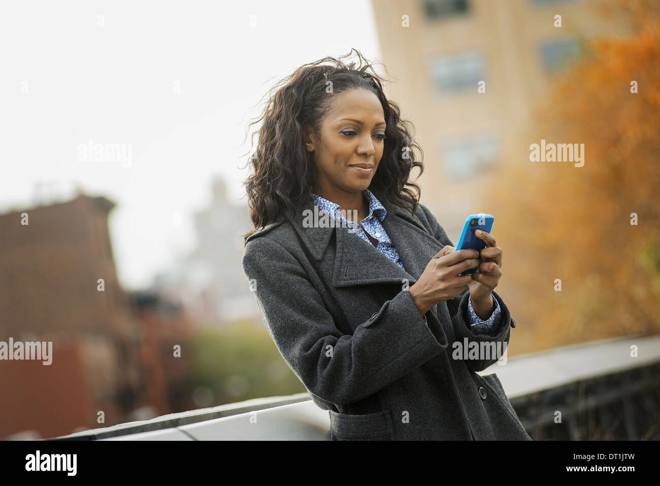 Eine Frau in einem Mantel zu überprüfen und SMS in Kontakt mit dem Handy telefonieren Stockfoto