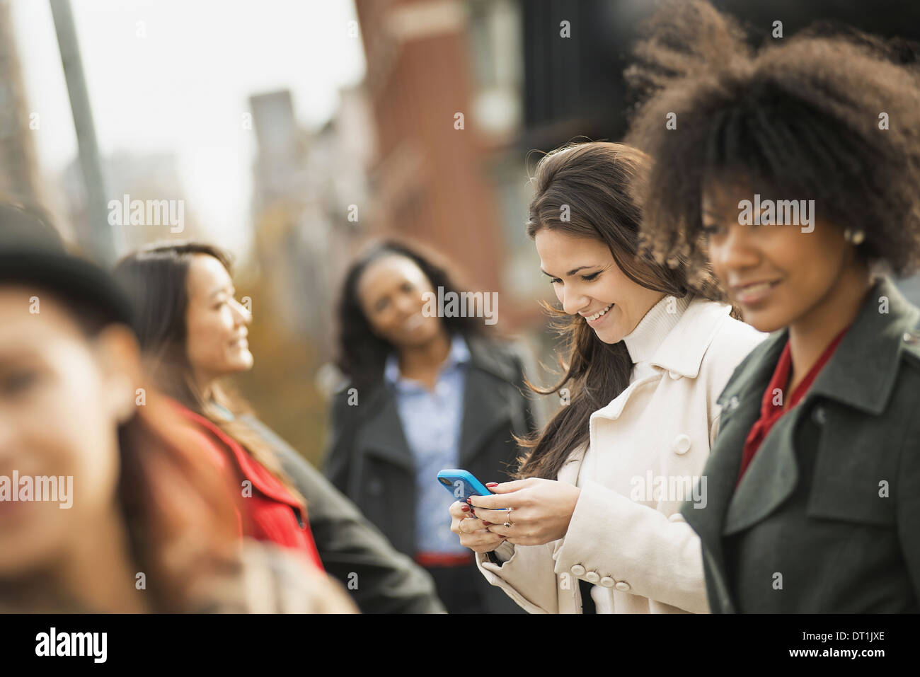 Benutzung von Mobiltelefonen und fünf Frauen miteinander zu reden Stockfoto