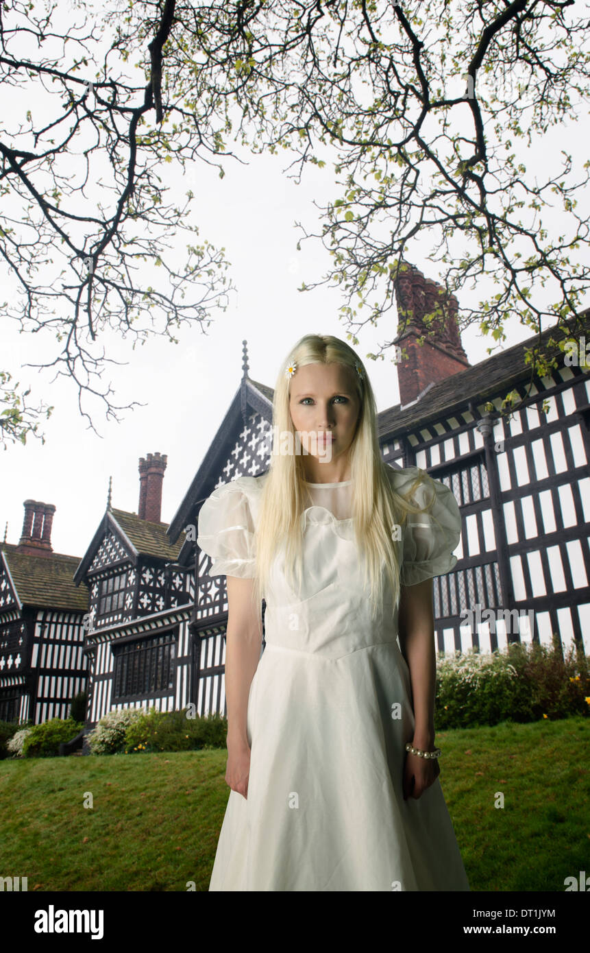 Frau im Vintage-Kleid stehen vor einem Tudor Haus Stockfoto