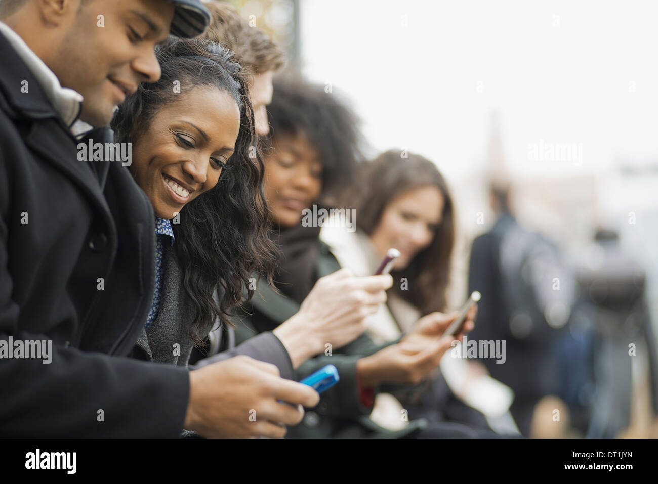 über die gehen Haltung in Kontakt mit Mobiltelefonen Männer und Frauen stehen in einer Linie auf der Suche, und lachen Stockfoto