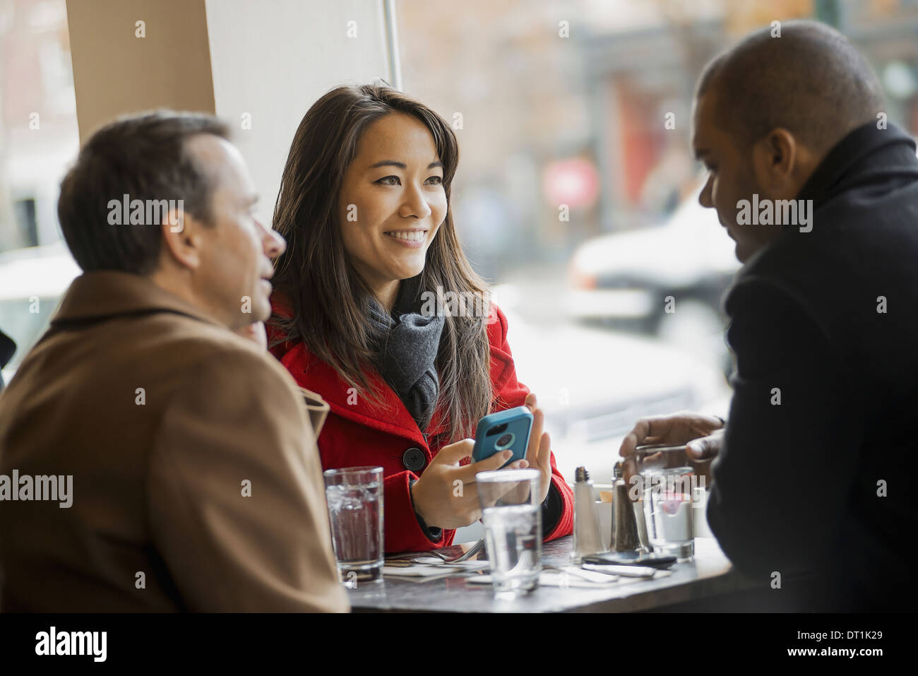 Eine Gruppe von Menschen auf die Benutzung von Mobiltelefonen und miteinander zu reden, In einem Café Stockfoto