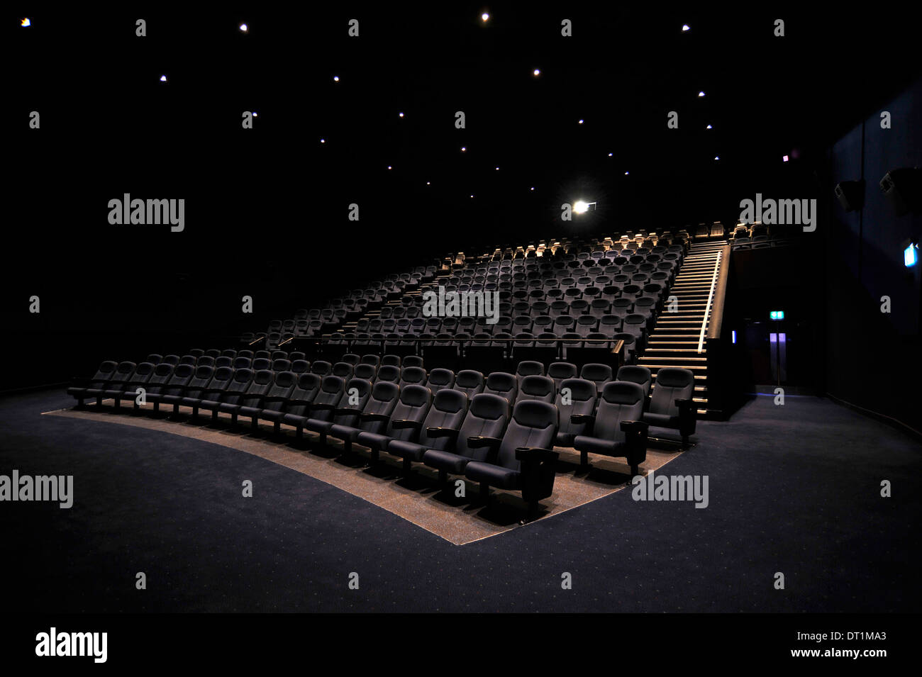Das Innere von einem Kinosaal mit Sitzreihen mit Blick auf eine Leinwand mit Projektor oben und dahinter Stockfoto