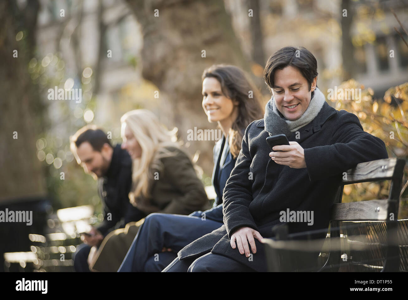 Gruppe auf Bank im Stadtpark mit smartphones Stockfoto