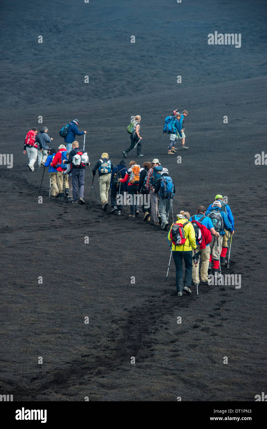 Touristen, die zu Fuß in einer Linie durch den Lava-Sand der Tolbachik Vulkan, Kamtschatka, Russland, Eurasia Stockfoto