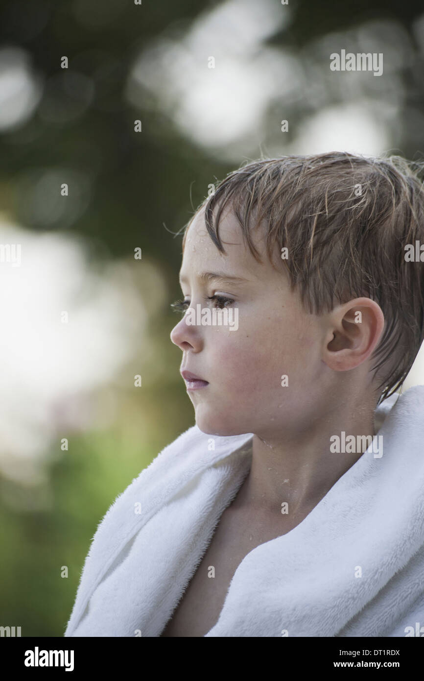 Ein kleiner Junge mit nassen Haaren nach dem Schwimmen in ein Handtuch gewickelt. Stockfoto