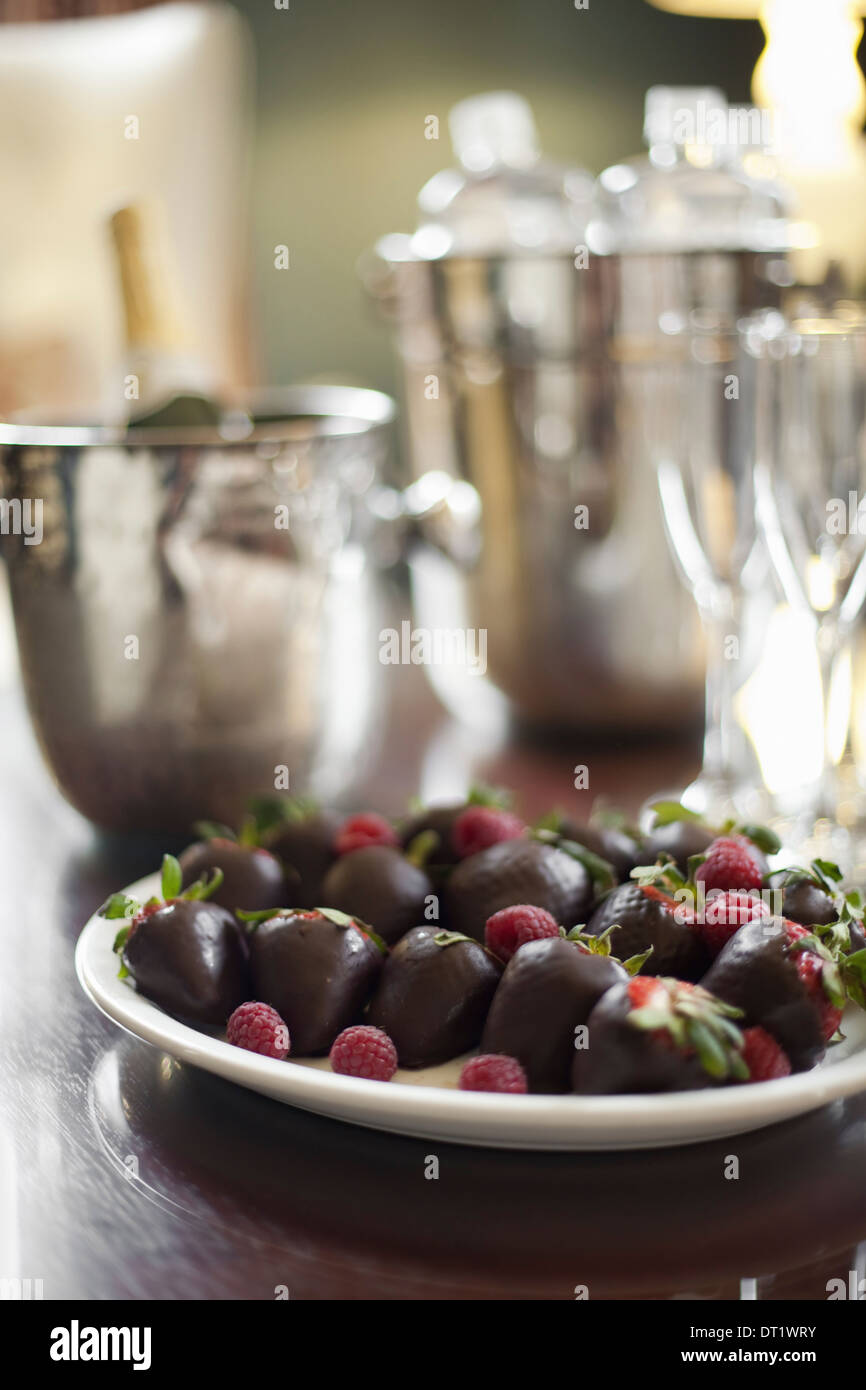 Platte von Hand getaucht Bio-Erdbeeren Früchte in handwerklichen handgeschöpfte Schokolade mit Himbeere garnieren Champagner und Gläser Stockfoto