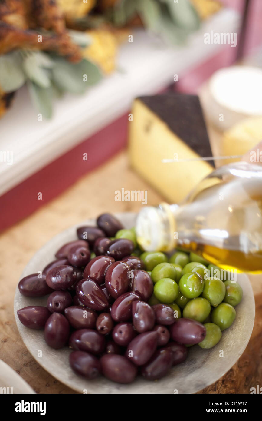 frisches Bio-Gemüse, grüne und schwarze Oliven Öl aus einer Flasche bereit Farm nieselt stehen Lebensmittel für eine Party Stockfoto