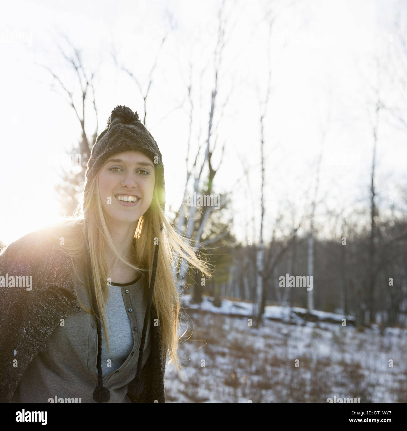Eine junge Frau mit blonden Haaren und eine wollene Mütze und Mantel im Freien an einem Wintertag Schnee auf dem Boden Stockfoto