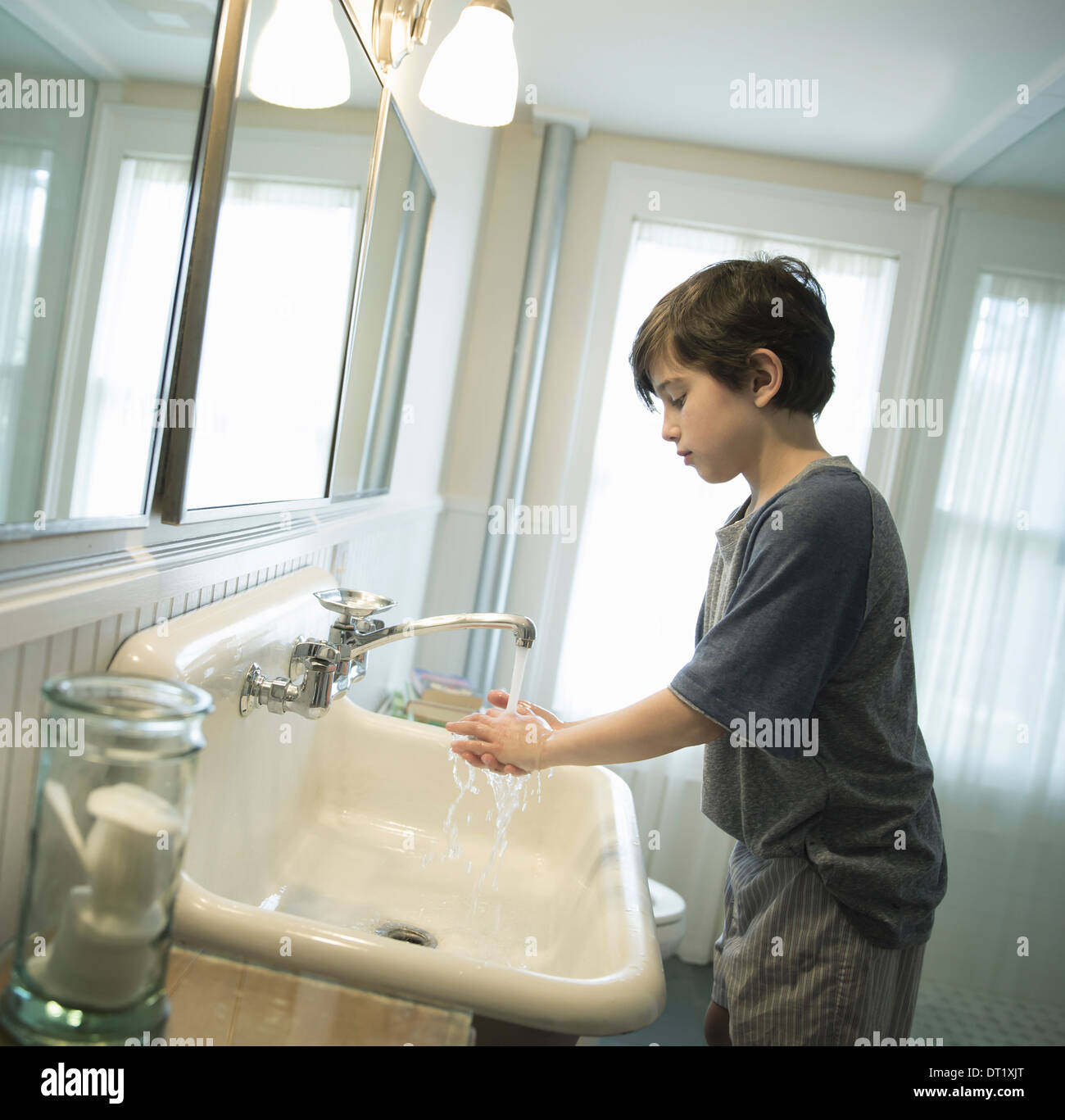 Ein Junge steht im Bad waschen seine Hände unter den Wasserhahn Stockfoto