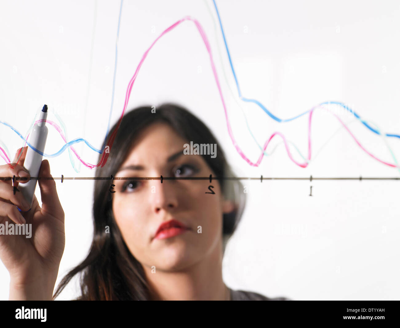 Eine junge Frau, die farbige Grafik Linien über eine Grafik Illustration auf einen durchsichtigen Oberfläche zeichnen Stockfoto