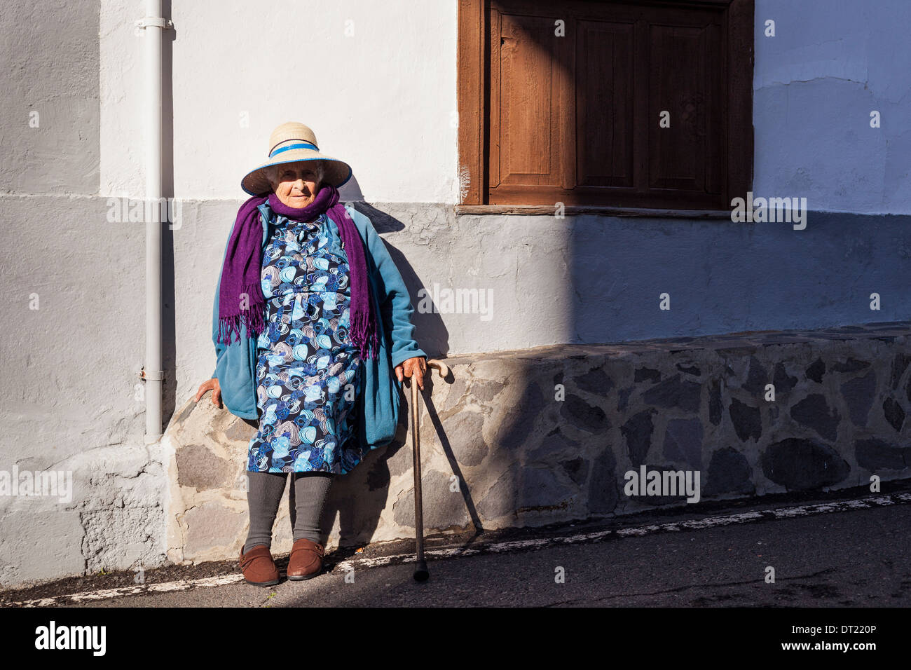Porträt von ältere Dame mit Strohhut, lila Schal und blauem Mantel in Arguayo, Teneriffa, Kanarische Inseln, Spanien. Stockfoto