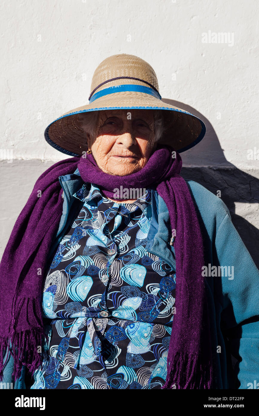 Porträt von ältere Dame mit Strohhut, lila Schal und blauem Mantel in Arguayo, Teneriffa, Kanarische Inseln, Spanien. Stockfoto